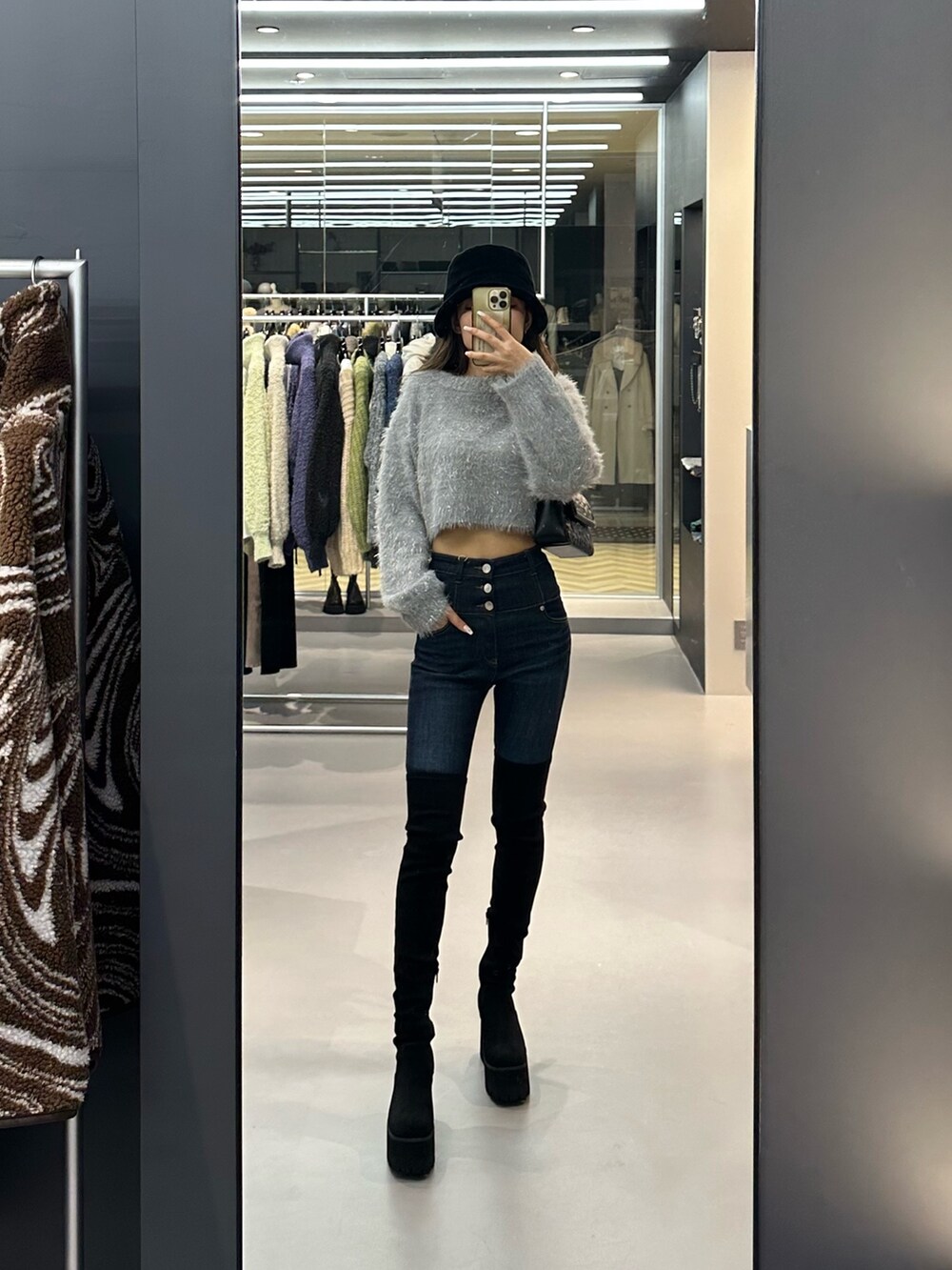 グレー系のニット/セーター、ブルー系のデニムパンツ、ブラック系のハンドバッグを着用したレディースの秋コーディネートの2枚目の写真