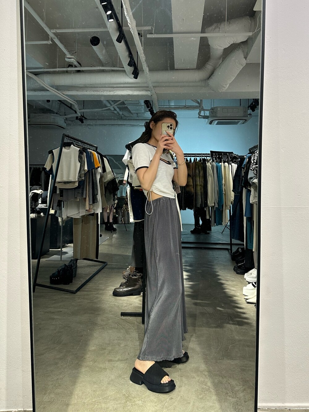 グレー系のスカート、ブラック系のサンダル、ホワイト系のTシャツ/カットソーを着用したレディースの夏コーディネートの2枚目の写真