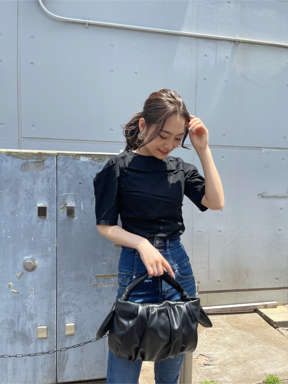 ブラック系のサンダル、ブラック系のハンドバッグ、ブラック系のTシャツ/カットソーを着用したレディースの夏コーディネートの2枚目の写真