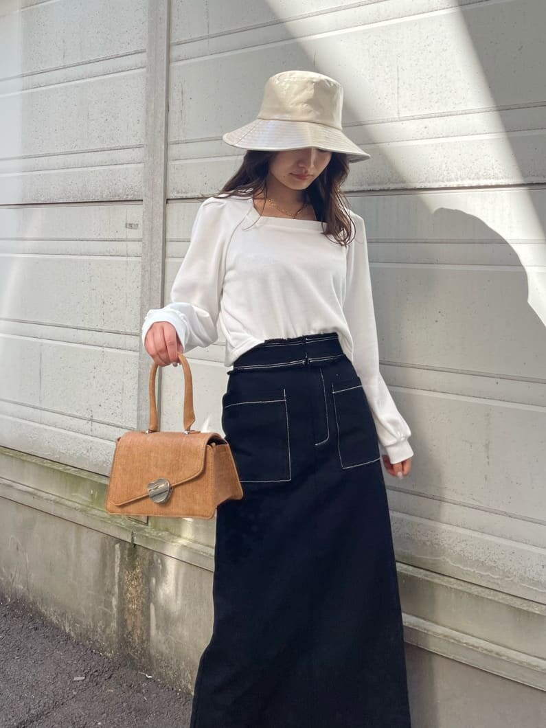 ブラック系のスカート、ホワイト系のTシャツ/カットソー、ブラウン系のハンドバッグを着用したレディースの冬コーディネートの2枚目の写真