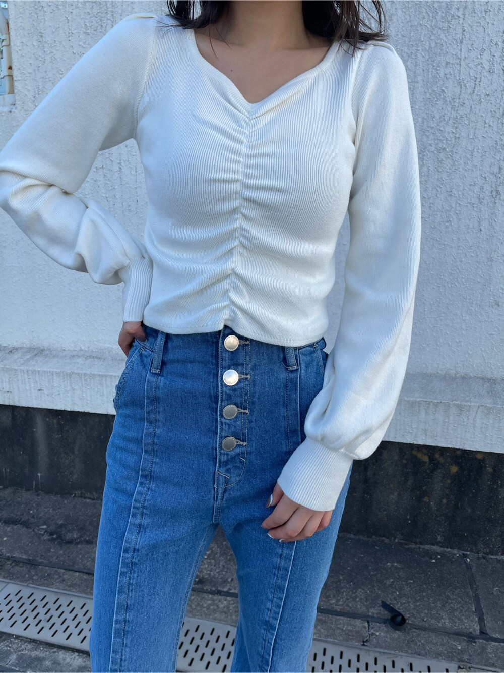 グリーン系のトレンチコート、ホワイト系のサンダル、ブルー系のデニムパンツを着用したレディースの冬コーディネートの4枚目の写真