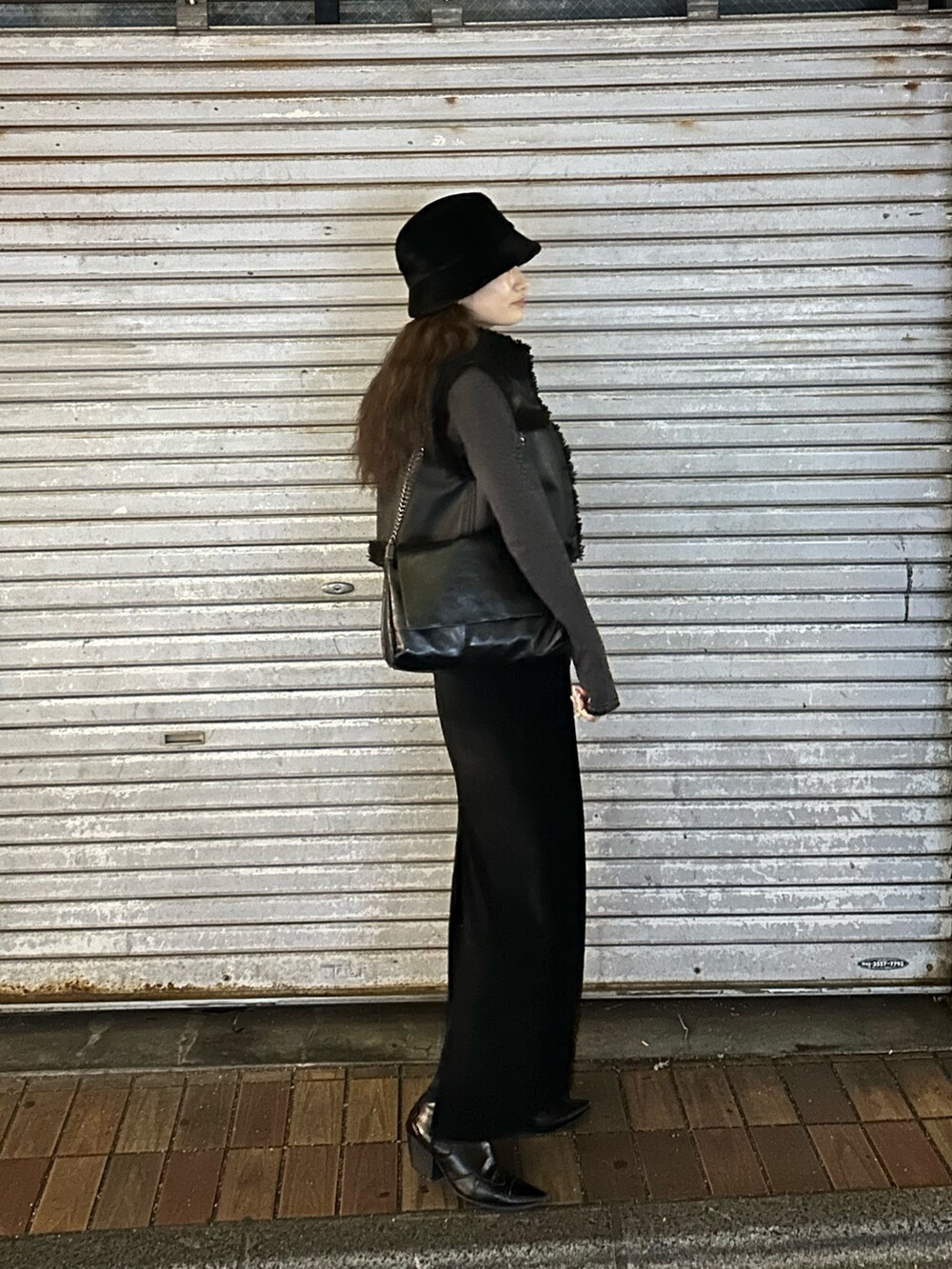 ブラック系のスカート、ブラック系のブーツ、ブラック系のハットを着用したレディースの冬コーディネートの3枚目の写真