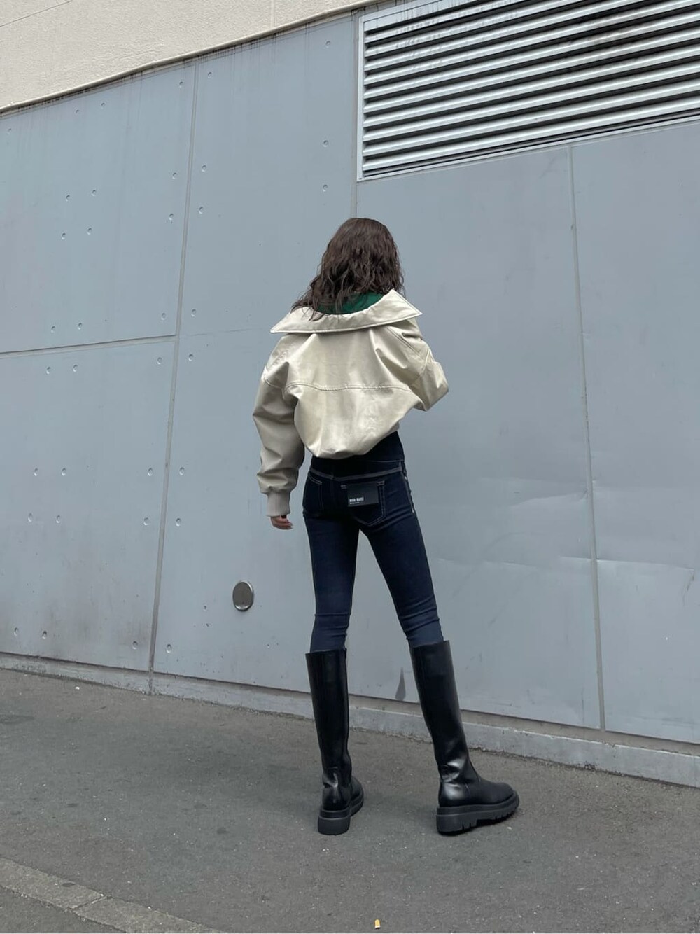 ホワイト系のブルゾン、ブラック系のブーツ、ブルー系のデニムパンツを着用したレディースの秋コーディネートの3枚目の写真