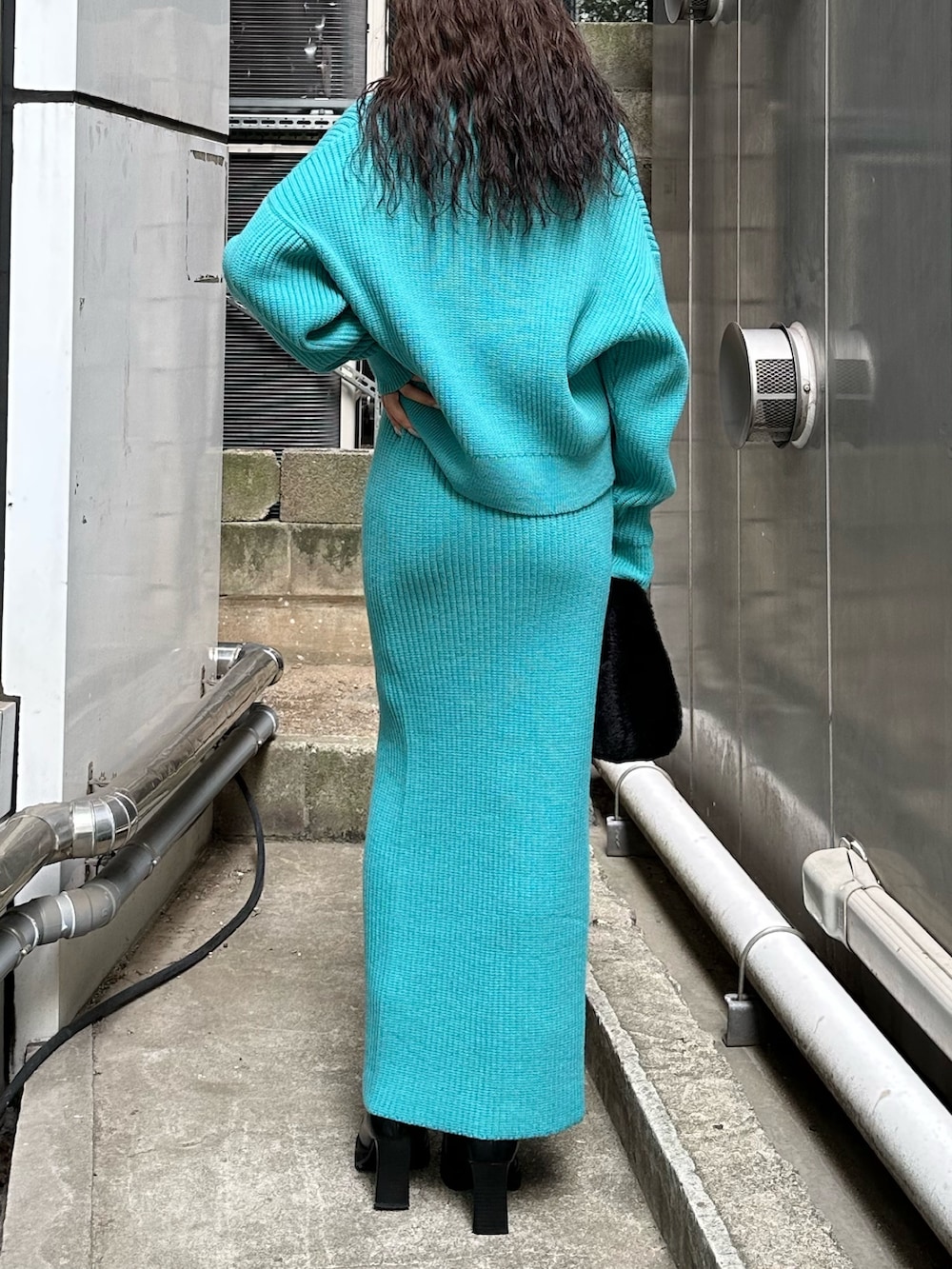 ブラック系のハンドバッグ、ブラック系のブーツ、ブルー系のスカートを着用したレディースの秋コーディネートの4枚目の写真