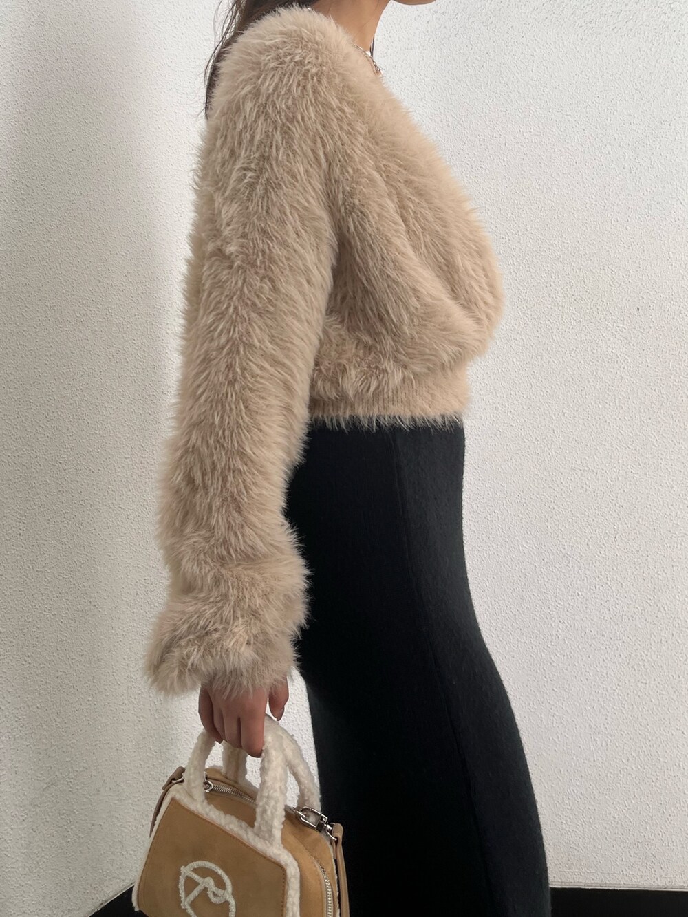 ホワイト系のニット/セーター、ベージュ系のハンドバッグ、ブラウン系のブーツを着用したレディースの秋コーディネートの5枚目の写真