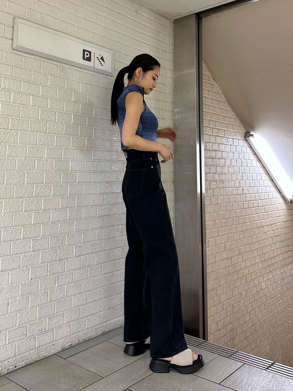 ブラック系のデニムパンツ、ブルー系のタンクトップ、ホワイト系のサンダルを着用したレディースの春コーディネートの2枚目の写真