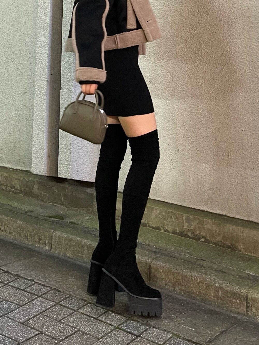 ブラック系のムートンコート、ブラウン系のハンドバッグ、ブラック系のブーツを着用したレディースの秋コーディネートの8枚目の写真