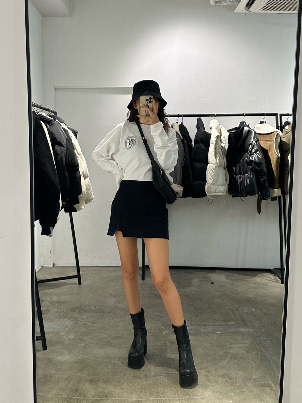 ブラック系のブーツ、ブラック系のスカート、ホワイト系のTシャツ/カットソーを着用したレディースの秋コーディネートの2枚目の写真