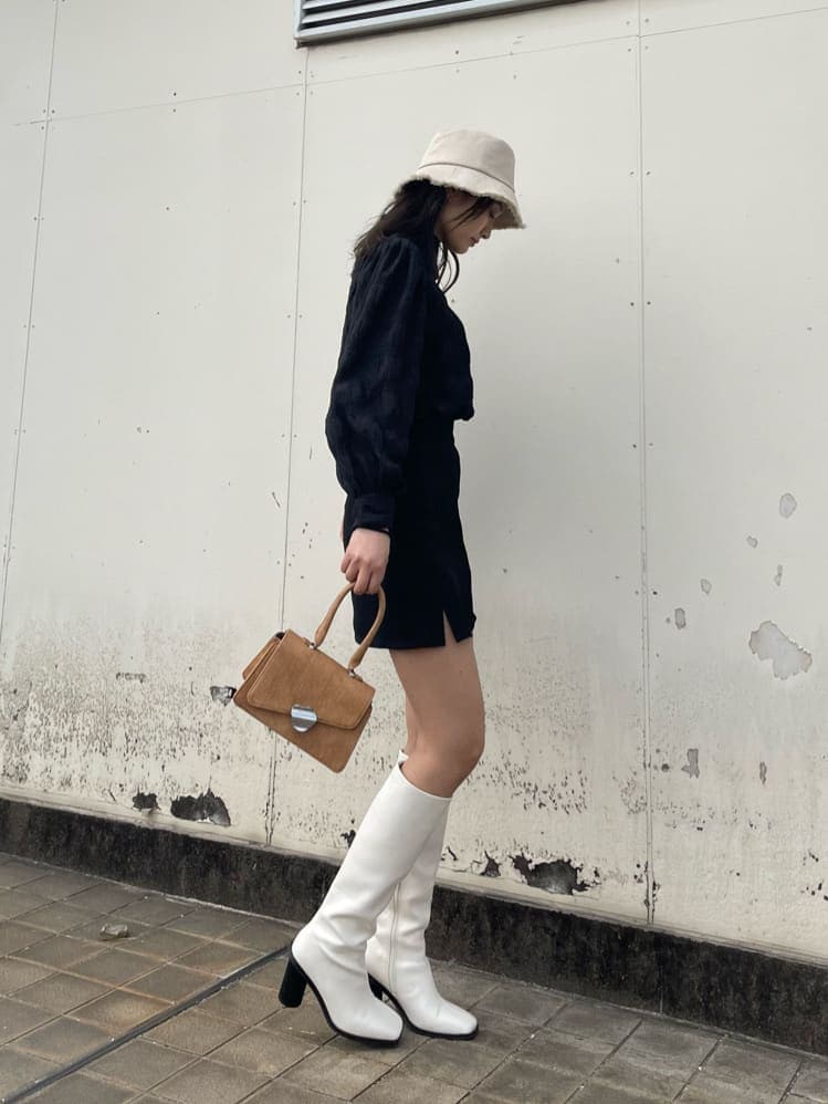 ホワイト系のブーツ、ブラウン系のハンドバッグ、ブラック系のシャツ/ブラウスを着用したレディースの春コーディネートの2枚目の写真