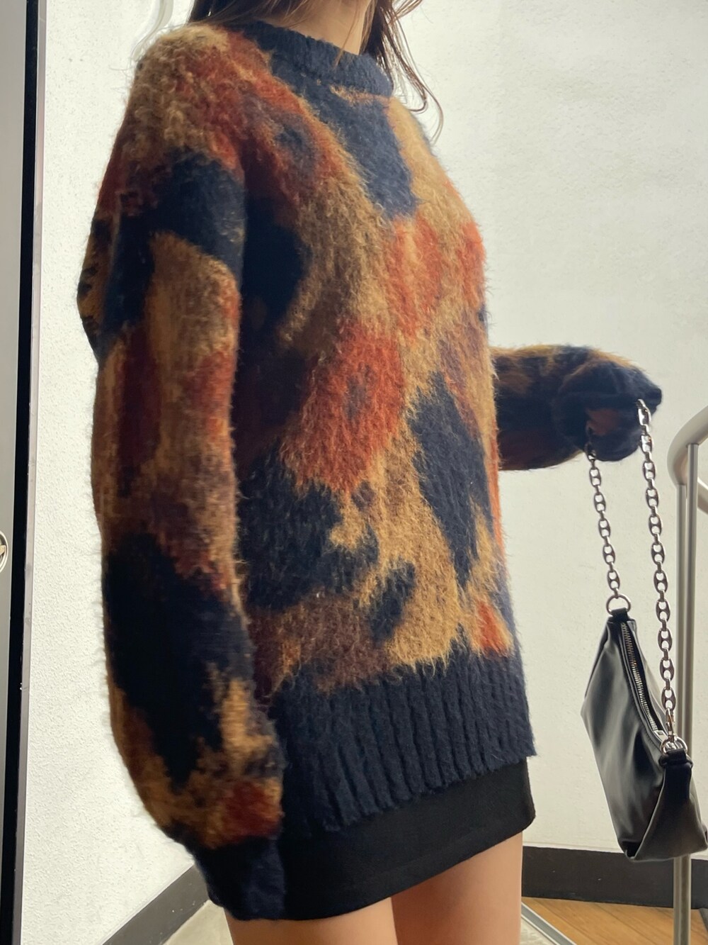 ブラック系のスカート、ブラック系のハンドバッグ、ブラック系のブーツを着用したレディースの秋コーディネートの6枚目の写真