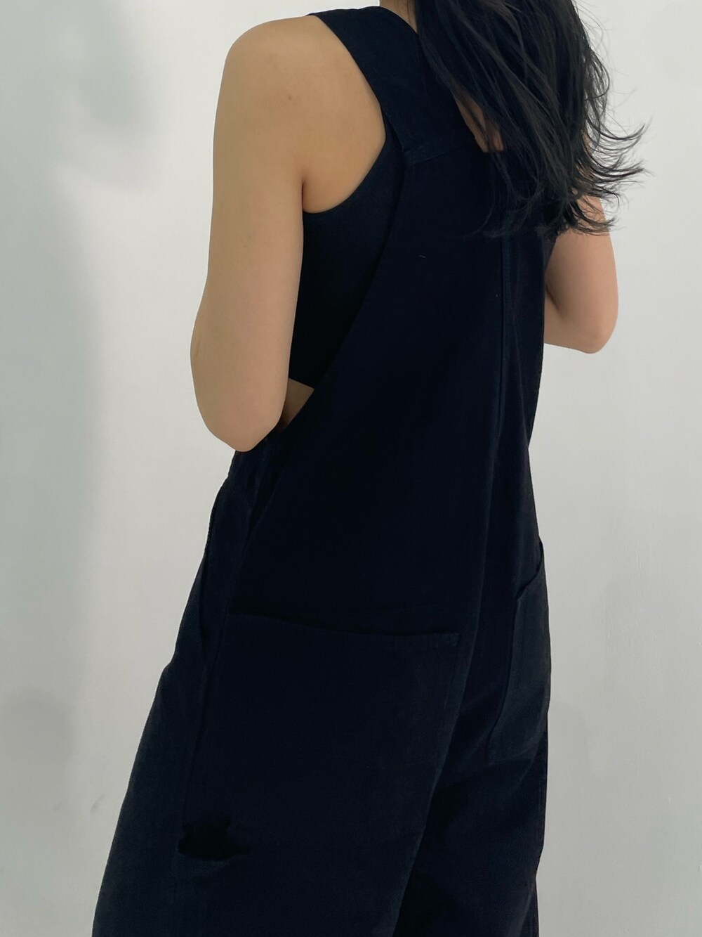 ブラック系のサロペット/オーバーオール、ホワイト系のハンドバッグ、ブラック系のサンダルを着用したレディースの春コーディネートの5枚目の写真