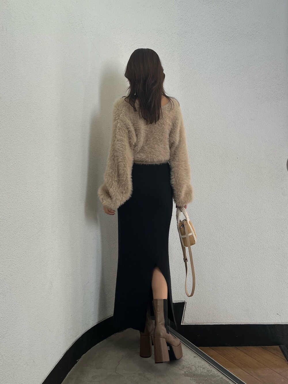 ホワイト系のニット/セーター、ベージュ系のハンドバッグ、ブラウン系のブーツを着用したレディースの秋コーディネートの3枚目の写真