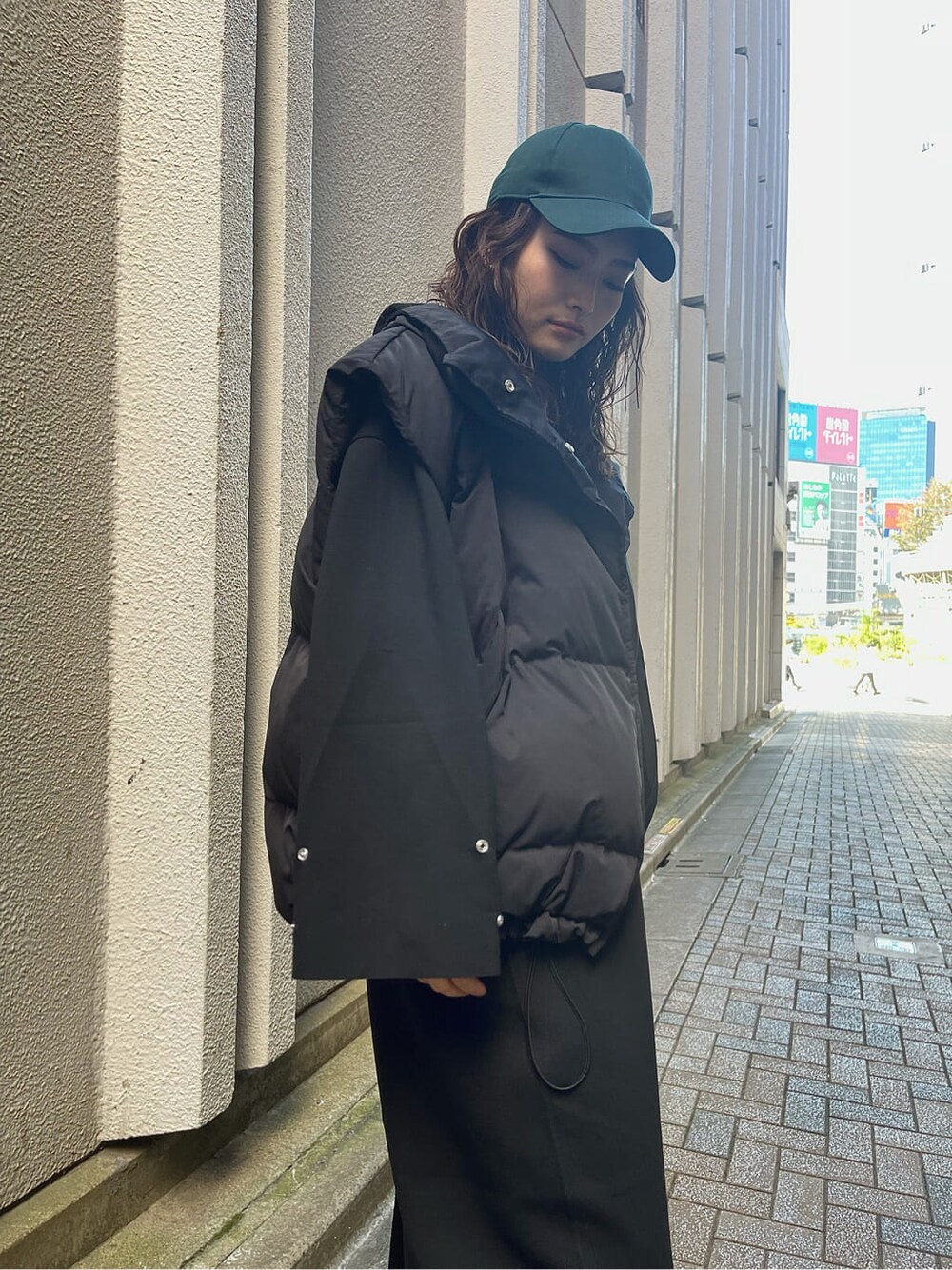 ブラック系のダウンベスト、ブラック系のワンピース、ブラック系のブーツを着用したレディースの秋コーディネートの9枚目の写真