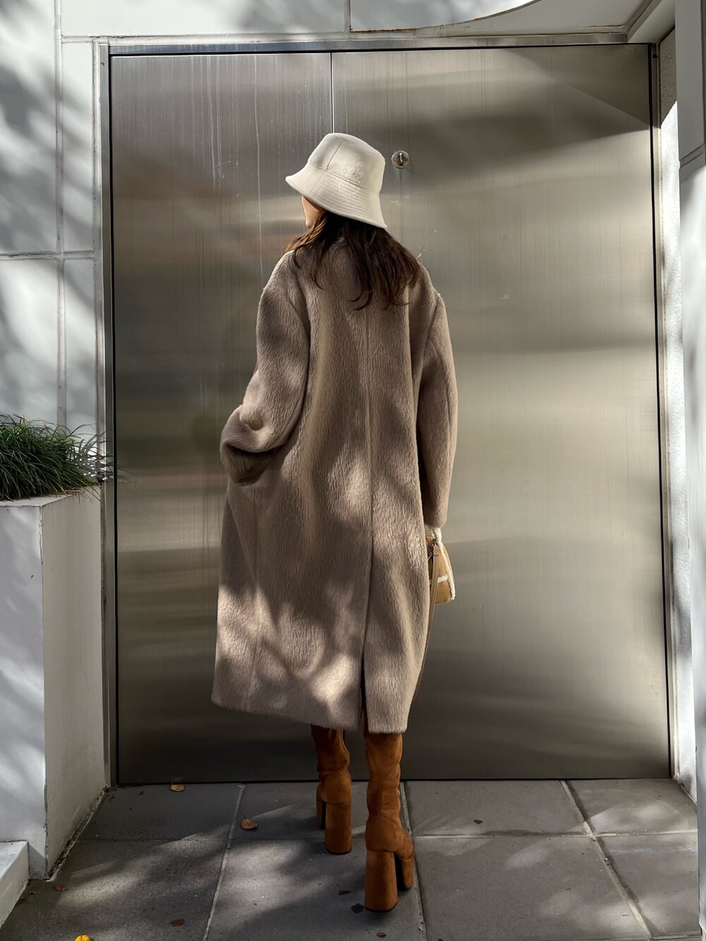 ブラック系のスカート、ベージュ系のハンドバッグ、ブラウン系のブーツを着用したレディースの秋コーディネートの3枚目の写真