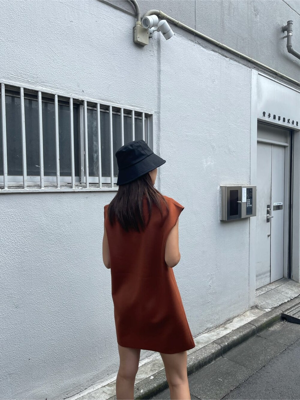 オレンジ系のワンピース、ブラック系のハンドバッグ、ブラック系のサンダルを着用したレディースの夏コーディネートの3枚目の写真