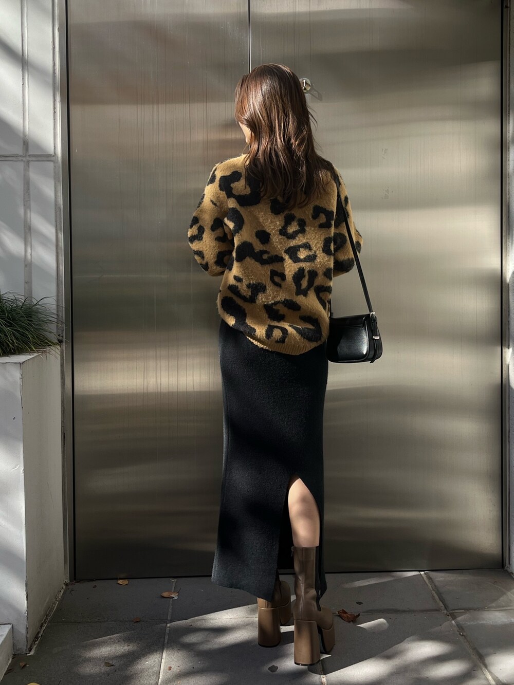 ベージュ系のニット/セーター、ブラウン系のブーツ、ブラック系のスカートを着用したレディースの秋コーディネートの3枚目の写真