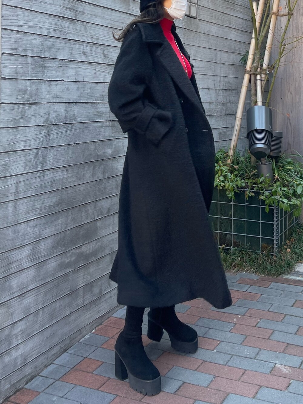 ブラック系のチェスターコート、その他のスカート、レッド系のニット/セーターを着用したレディースの冬コーディネートの4枚目の写真