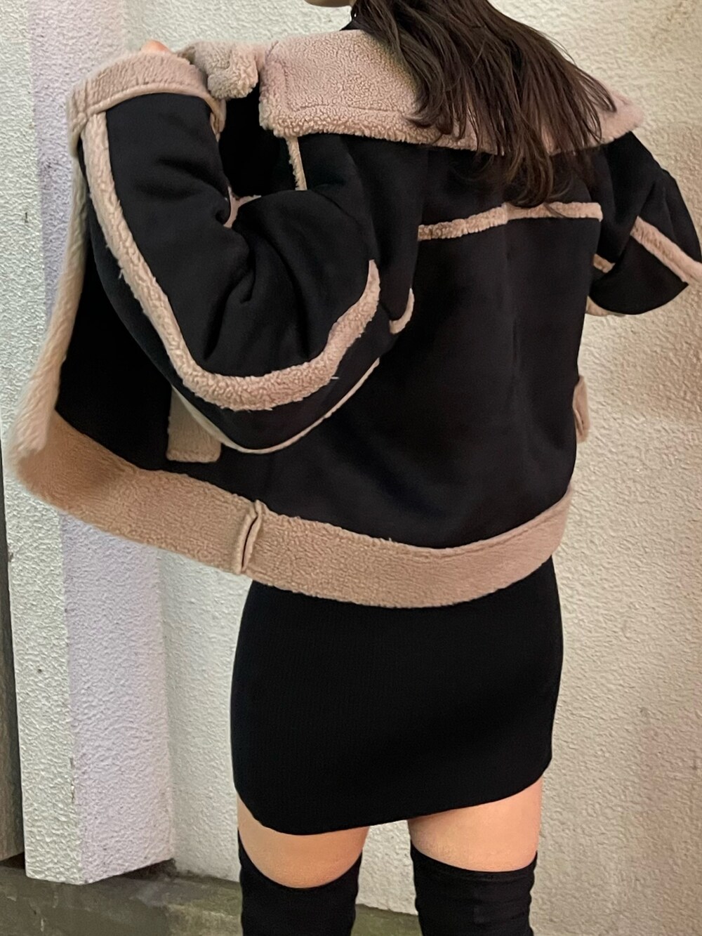 ブラック系のムートンコート、ブラウン系のハンドバッグ、ブラック系のブーツを着用したレディースの秋コーディネートの6枚目の写真