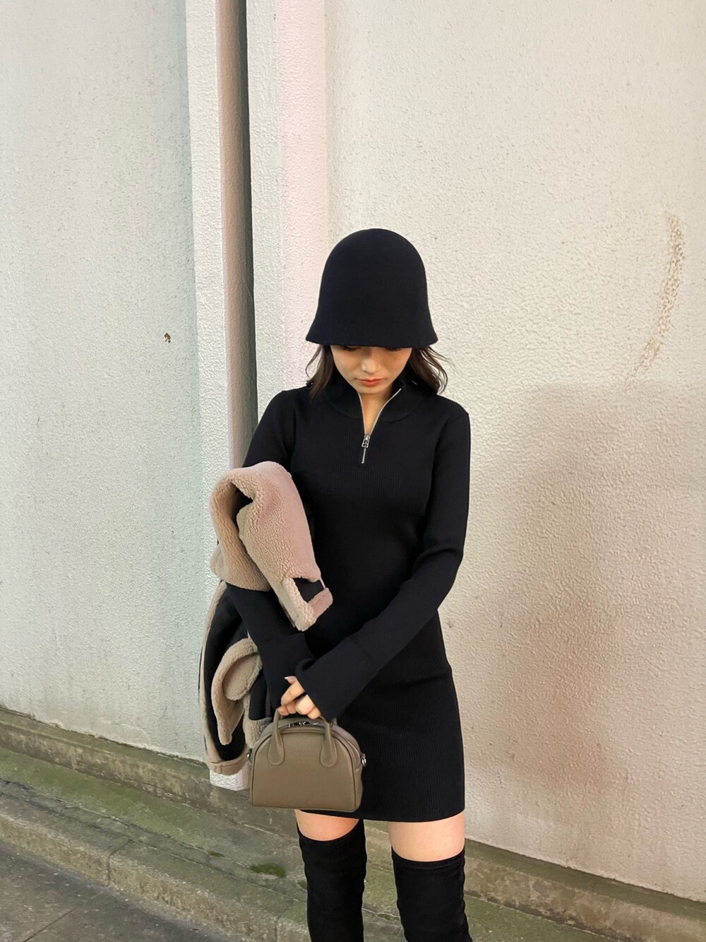 ブラック系のムートンコート、ブラウン系のハンドバッグ、ブラック系のブーツを着用したレディースの秋コーディネートの7枚目の写真