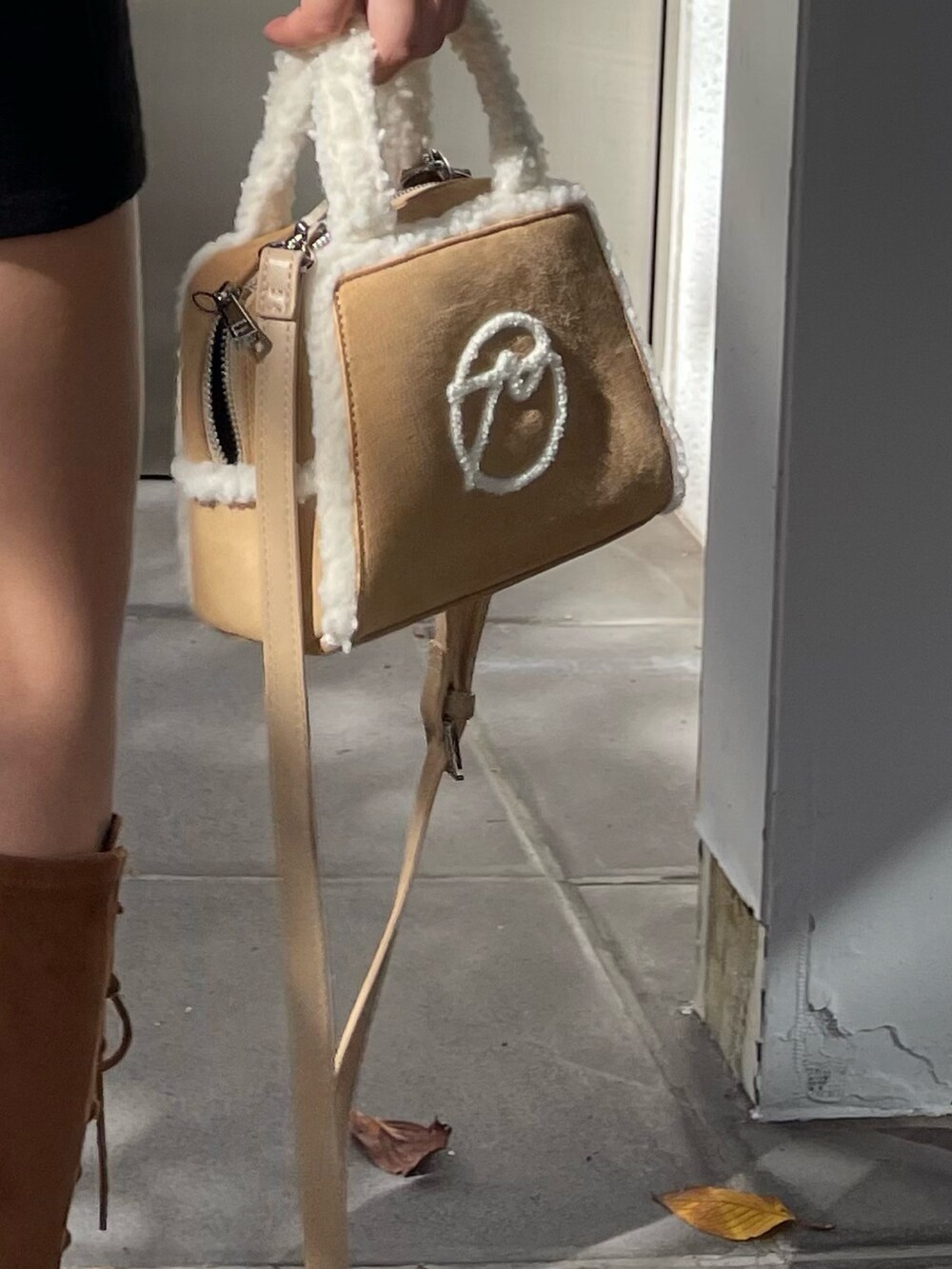 ブラック系のスカート、ベージュ系のハンドバッグ、ブラウン系のブーツを着用したレディースの秋コーディネートの7枚目の写真