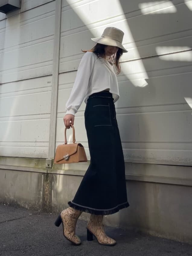 ブラック系のスカート、ホワイト系のTシャツ/カットソー、ブラウン系のハンドバッグを着用したレディースの冬コーディネートの3枚目の写真