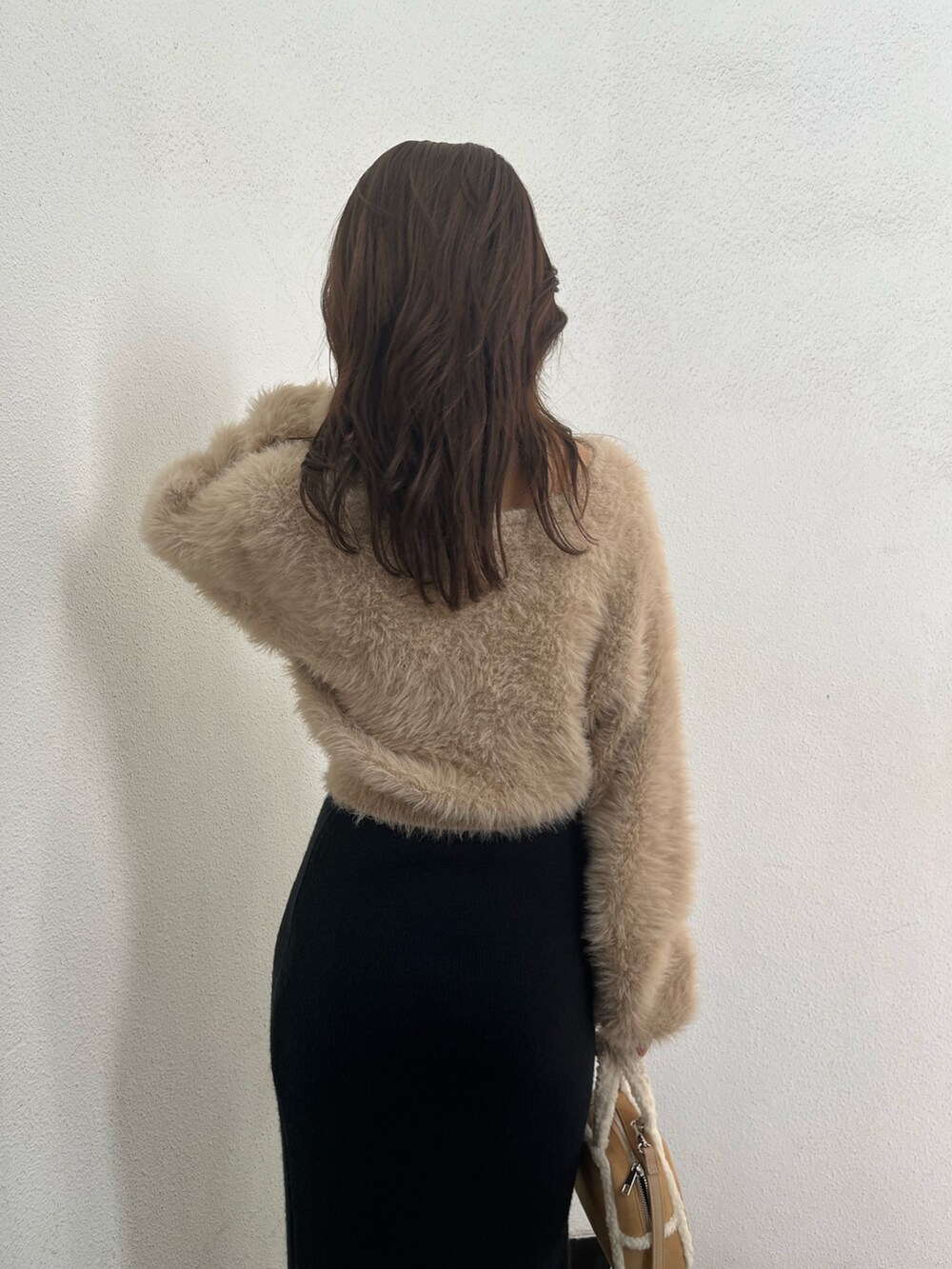 ホワイト系のニット/セーター、ベージュ系のハンドバッグ、ブラウン系のブーツを着用したレディースの秋コーディネートの6枚目の写真