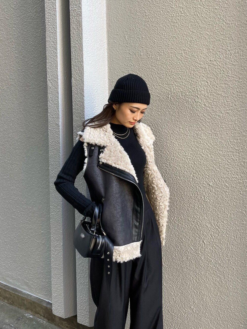 ブラック系のニット/セーター、ブラック系のその他パンツ、ブラック系のハンドバッグを着用したレディースの冬コーディネートの4枚目の写真