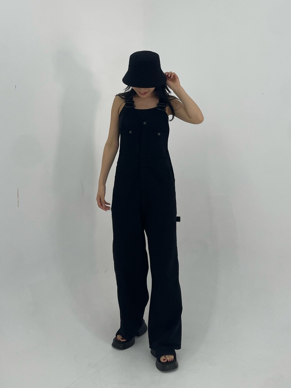 ブラック系のサロペット/オーバーオール、ホワイト系のハンドバッグ、ブラック系のサンダルを着用したレディースの春コーディネートの2枚目の写真