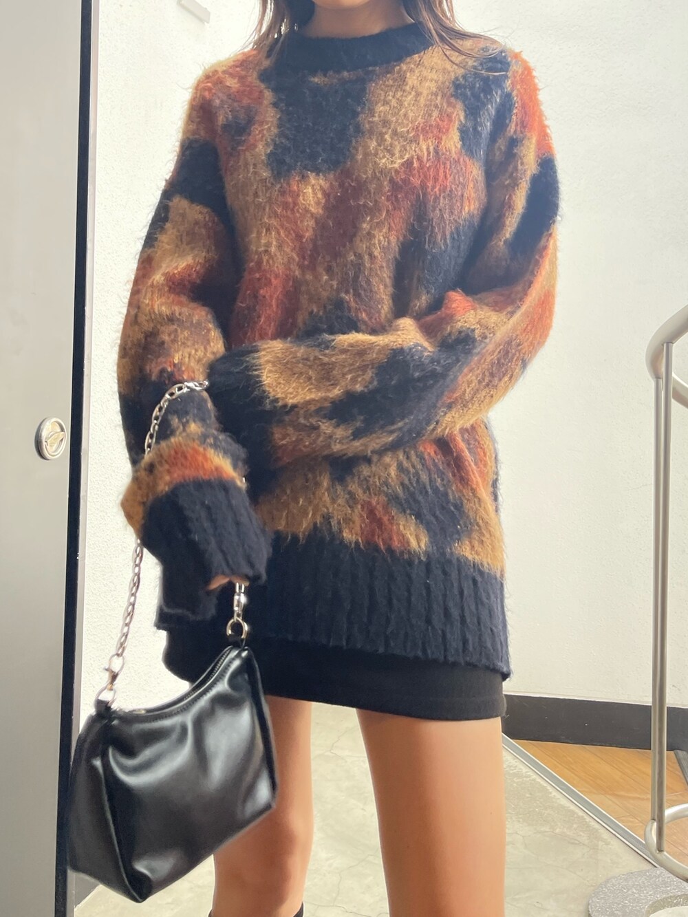 ブラック系のスカート、ブラック系のハンドバッグ、ブラック系のブーツを着用したレディースの秋コーディネートの4枚目の写真