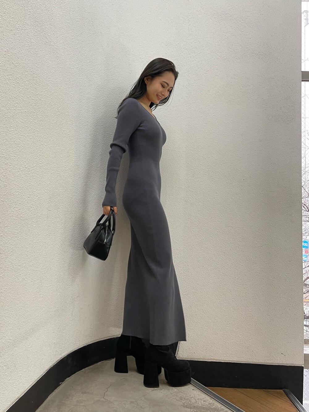 グレー系のワンピース、ブラック系のハンドバッグ、ブラック系のブーツを着用したレディースの冬コーディネートの4枚目の写真