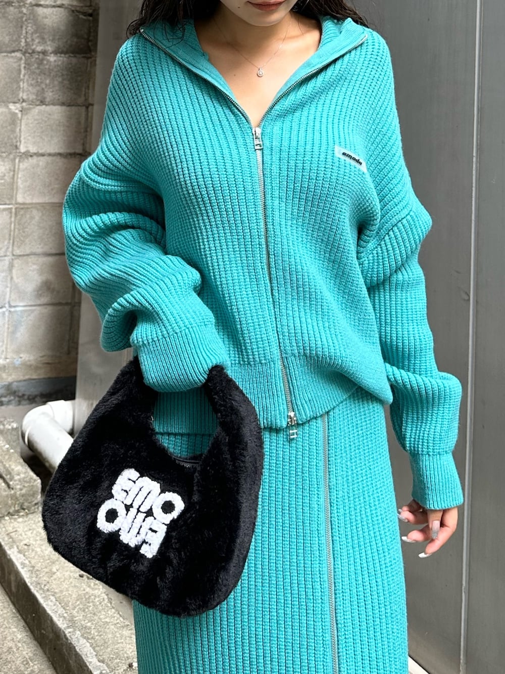 ブラック系のハンドバッグ、ブラック系のブーツ、ブルー系のスカートを着用したレディースの秋コーディネートの6枚目の写真