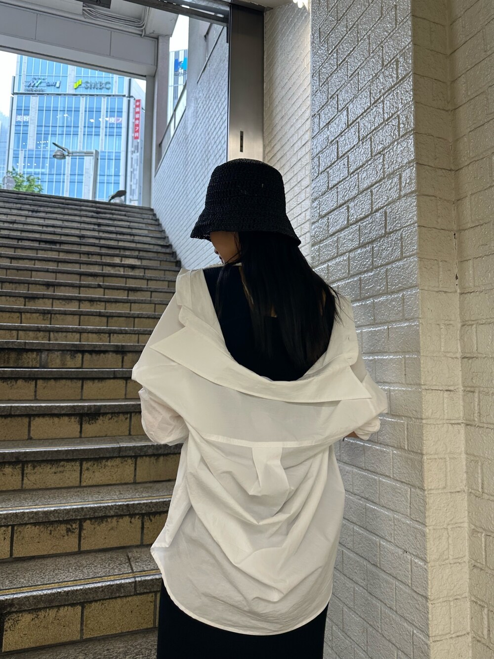 ブラック系のワンピース、ホワイト系のシャツ/ブラウス、ホワイト系のサンダルを着用したレディースの春コーディネートの5枚目の写真