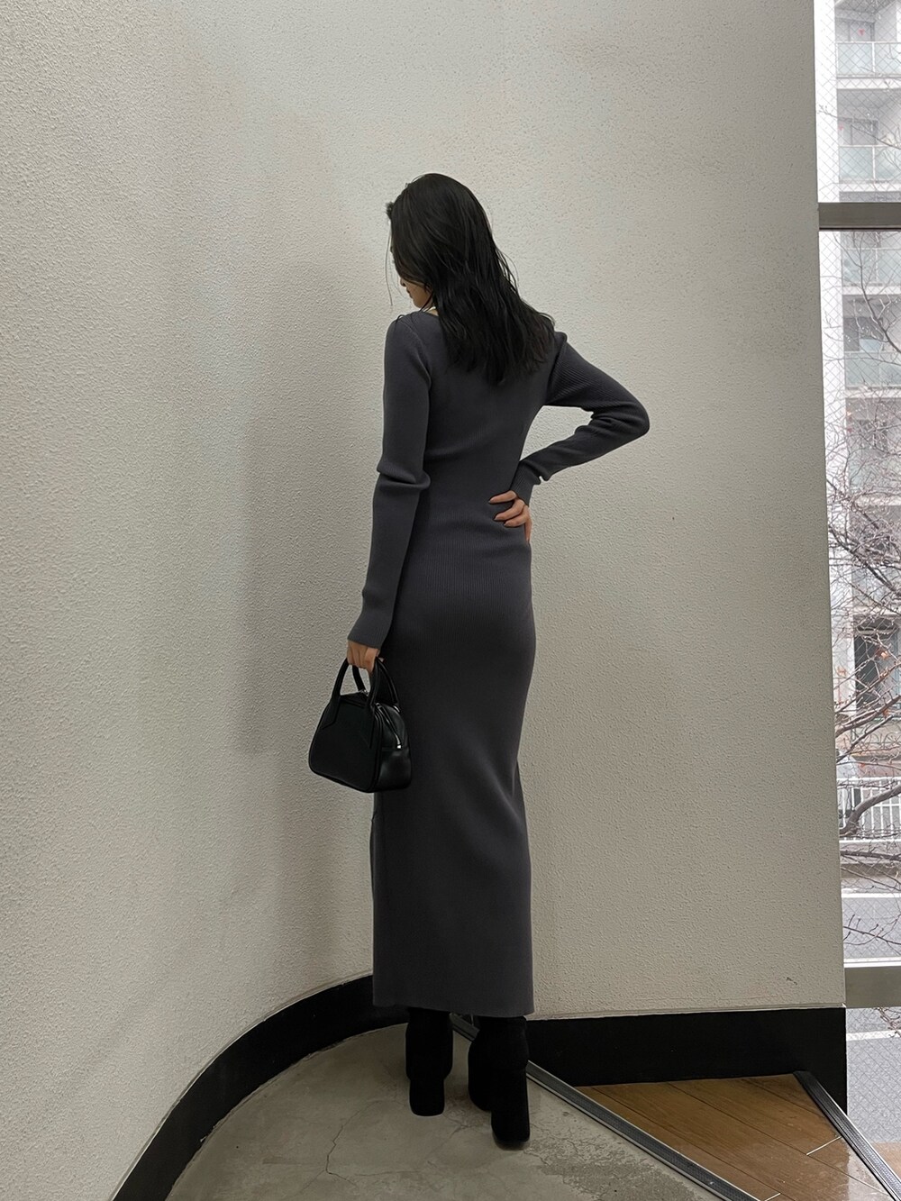 グレー系のワンピース、ブラック系のハンドバッグ、ブラック系のブーツを着用したレディースの冬コーディネートの5枚目の写真