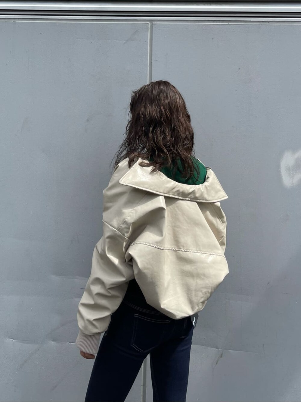 ホワイト系のブルゾン、ブラック系のブーツ、ブルー系のデニムパンツを着用したレディースの秋コーディネートの5枚目の写真