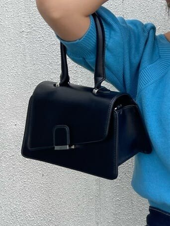 ブラック系のハンドバッグ、ブルー系のデニムパンツ、ブルー系のニット/セーターを着用したレディースの秋コーディネートの6枚目の写真