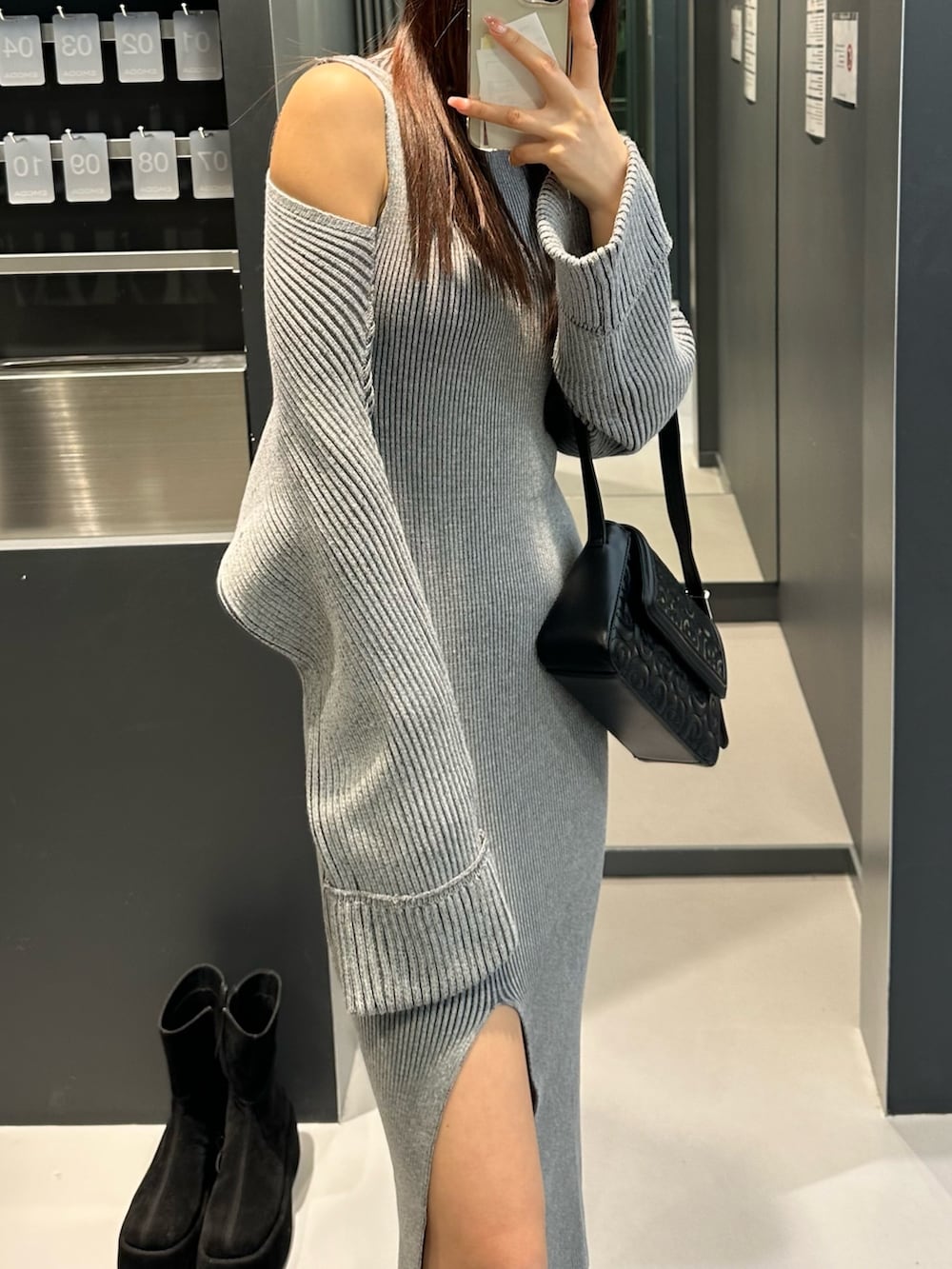 グレー系のワンピース、ブラック系のブーツ、ブラック系のハンドバッグを着用したレディースの冬コーディネートの3枚目の写真