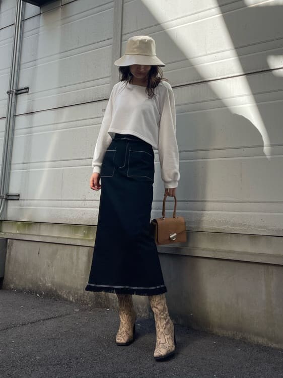 ブラック系のスカート、ホワイト系のTシャツ/カットソー、ブラウン系のハンドバッグを着用したレディースの冬コーディネートの4枚目の写真