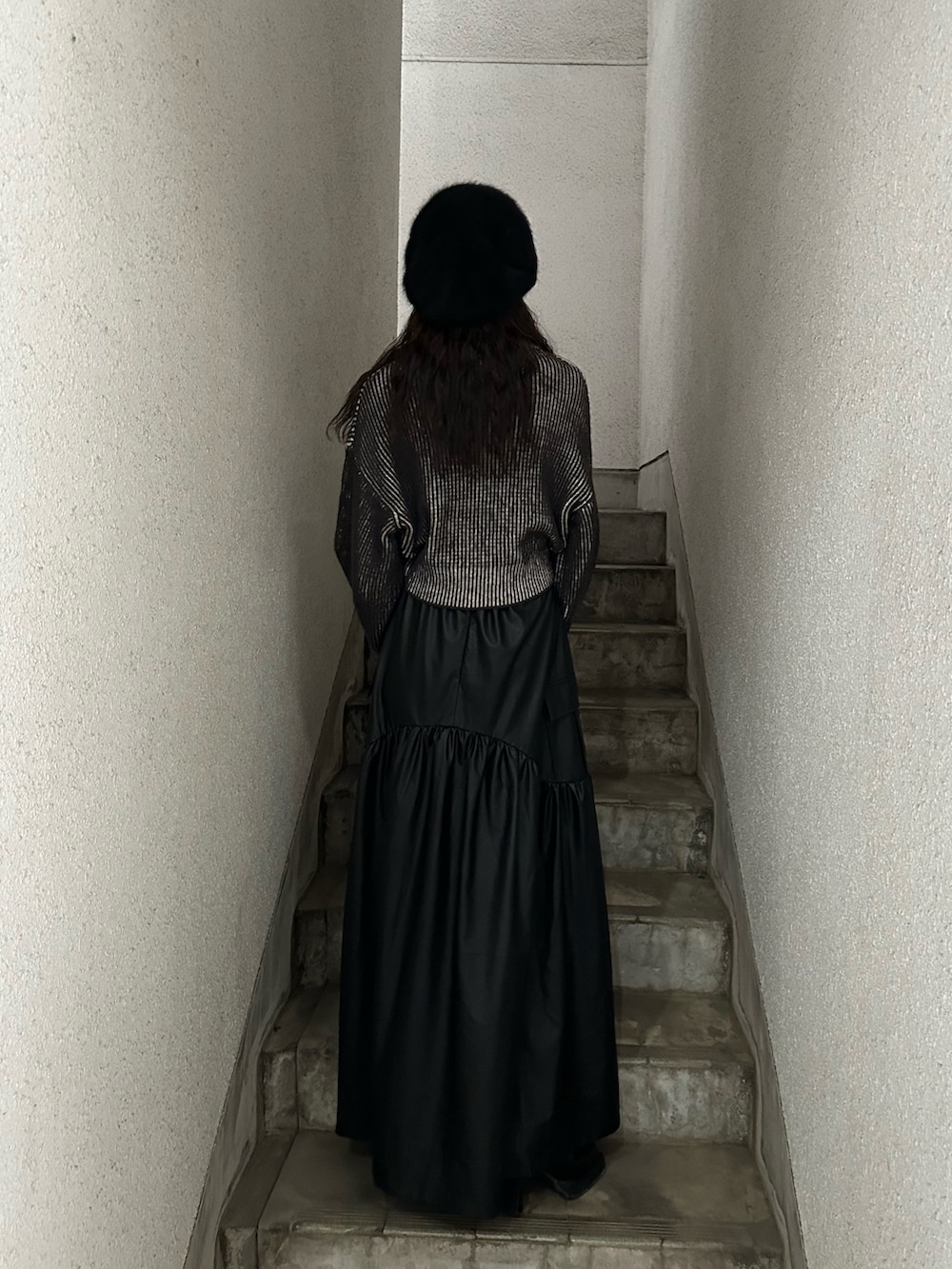 ブラック系のスカート、ブラック系のニット/セーター、ブラック系のハンドバッグを着用したレディースの秋コーディネートの2枚目の写真