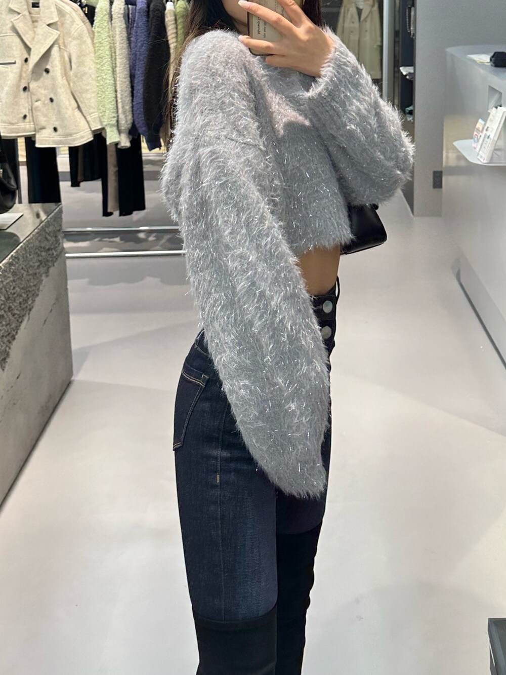 グレー系のニット/セーター、ブルー系のデニムパンツ、ブラック系のハンドバッグを着用したレディースの秋コーディネートの3枚目の写真