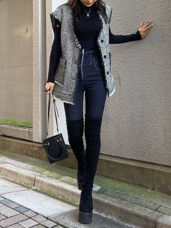 ブルー系のデニムパンツ、グレー系のベスト、ブラック系のニット/セーターを着用したレディースの秋コーディネートの2枚目の写真