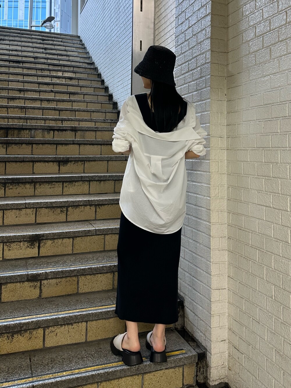 ブラック系のワンピース、ホワイト系のシャツ/ブラウス、ホワイト系のサンダルを着用したレディースの春コーディネートの3枚目の写真