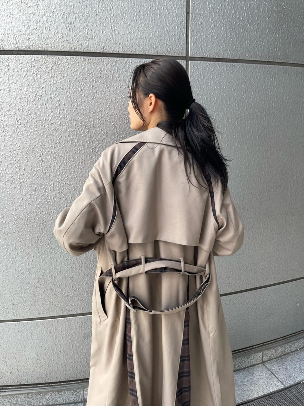 ベージュ系のトレンチコート、ブラック系のTシャツ/カットソー、ブラック系のデニムパンツを着用したレディースの夏コーディネートの3枚目の写真