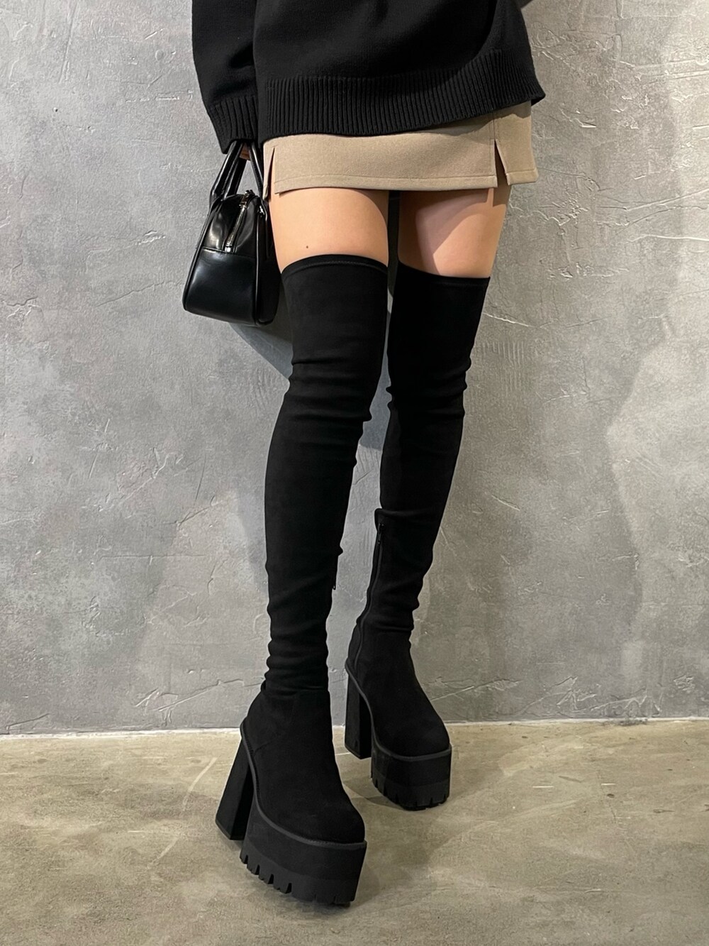 ブラック系のニット/セーター、ベージュ系のスカート、ブラック系のブーツを着用したレディースの冬コーディネートの7枚目の写真