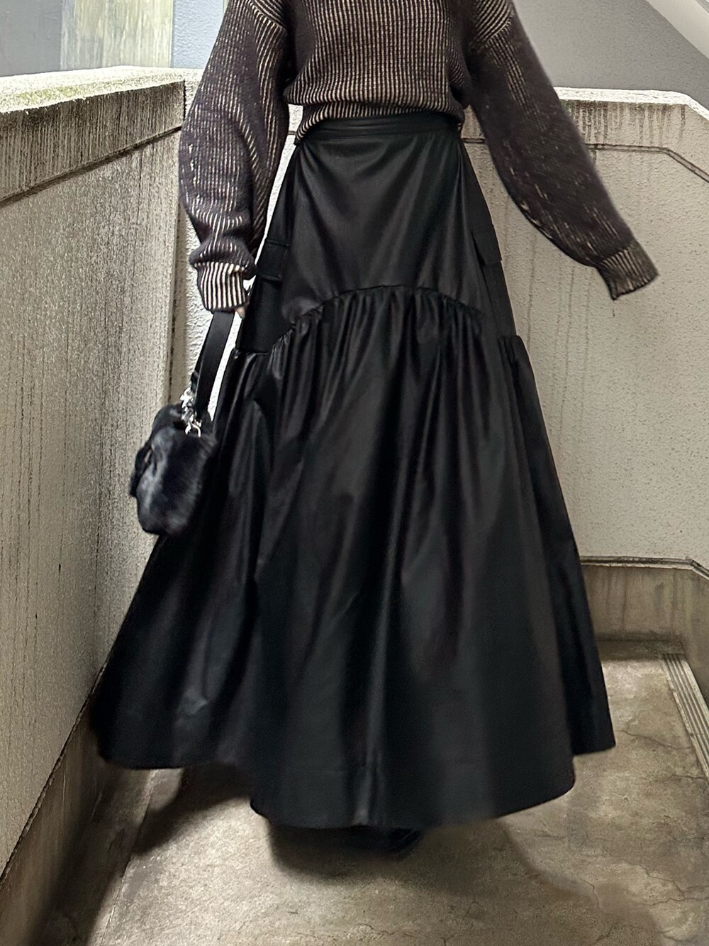 ブラック系のスカート、ブラック系のニット/セーター、ブラック系のハンドバッグを着用したレディースの秋コーディネートの7枚目の写真