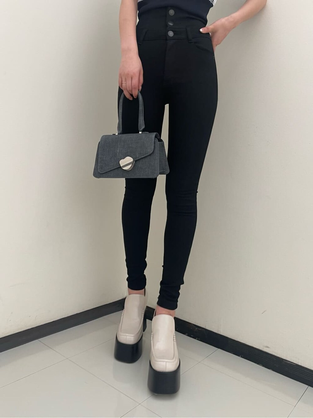 ホワイト系のローファー、ブラック系のハンドバッグ、ブラック系のデニムパンツを着用したレディースの春コーディネートの5枚目の写真