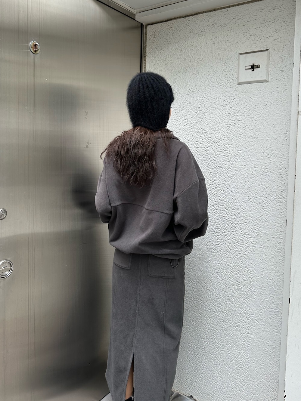 グレー系のTシャツ/カットソー、グレー系のスカート、ブラック系のブーツを着用したレディースの秋コーディネートの5枚目の写真