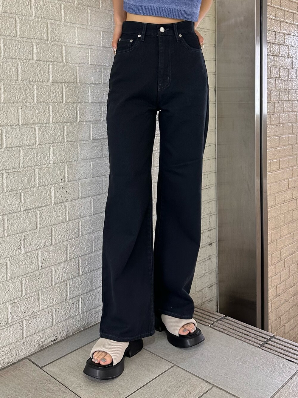 ブラック系のデニムパンツ、ブルー系のタンクトップ、ホワイト系のサンダルを着用したレディースの春コーディネートの6枚目の写真