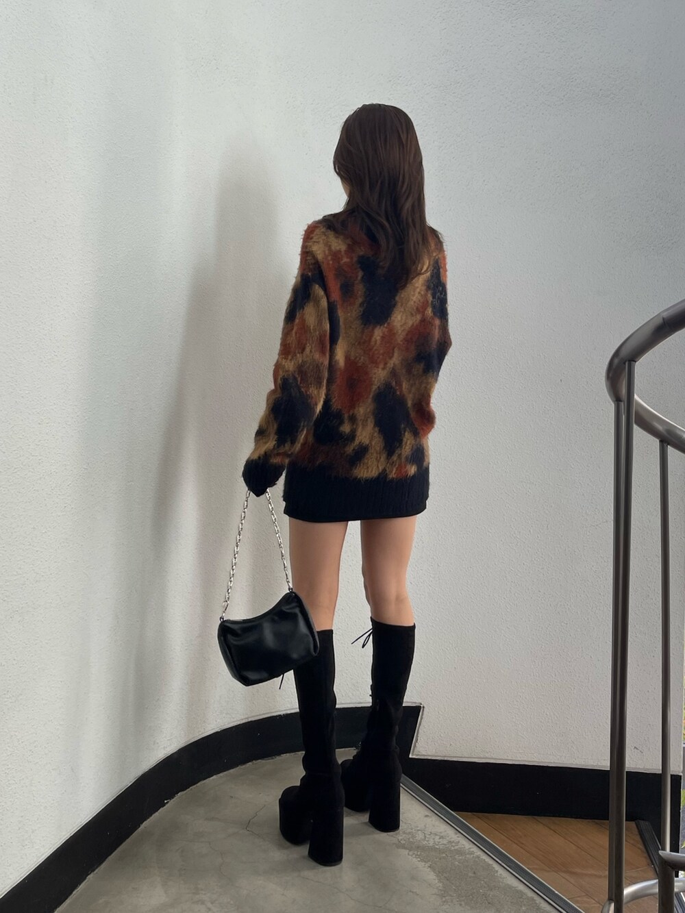 ブラック系のスカート、ブラック系のハンドバッグ、ブラック系のブーツを着用したレディースの秋コーディネートの3枚目の写真