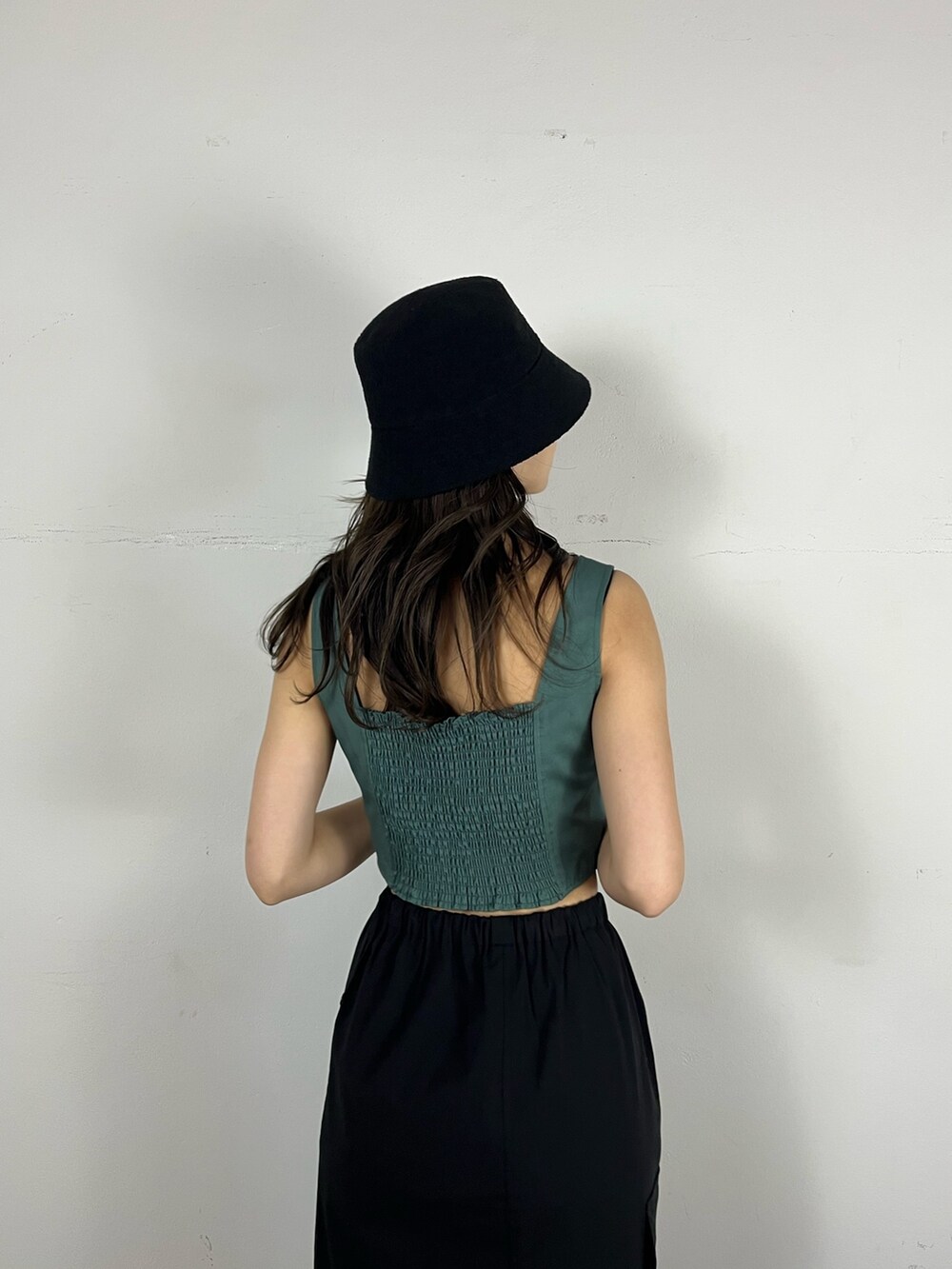 ブラック系のスカート、グリーン系のキャミソール、ブラック系のブーツを着用したレディースの春コーディネートの4枚目の写真