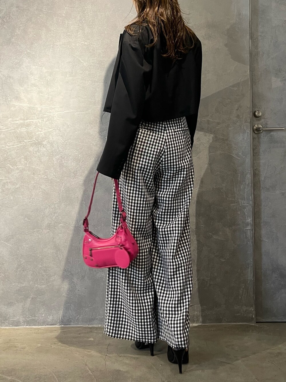 ピンク系のハンドバッグ、ブラック系のパンプス、ブラック系のテーラードジャケットを着用したレディースの冬コーディネートの3枚目の写真